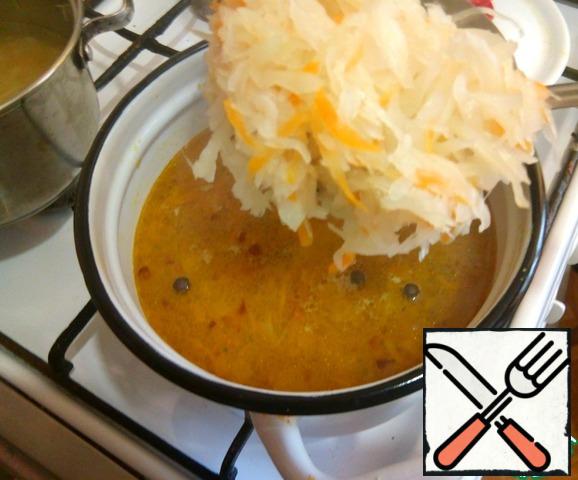 Now use a slotted spoon to put the cooked sauerkraut in a common saucepan with vegetables, bring to a boil. Taste the soup, add salt and cabbage broth, adjust the acidity of the soup to your liking.