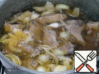 Pour boiled water over the meat, bring to a boil, put the onion cut into quarters and whole garlic cloves.