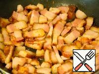 While the peas are cooking, fry the bacon pieces in a frying pan.