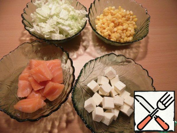 Cut the fish and tofu into cubes, finely chop the cabbage, drain the liquid from the corn.