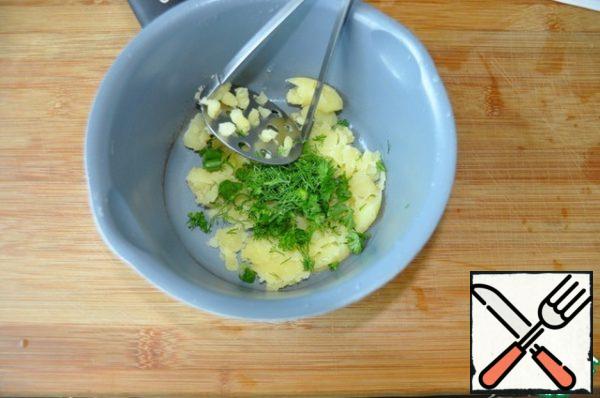 Peel the potatoes and mash them together with half of the chopped greens with a potato masher.
