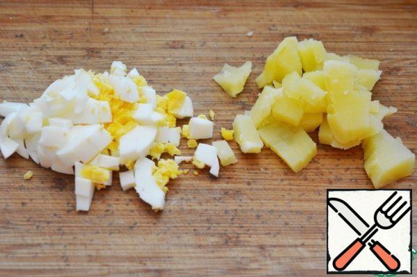 Cook potatoes in a peel, boil hard boiled eggs, cool them and cut them into cubes.