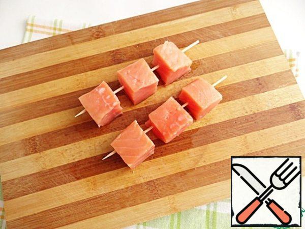 Cut the salmon into cubes into 6 or 8 pieces. Thread the salmon cubes on wooden skewers.
