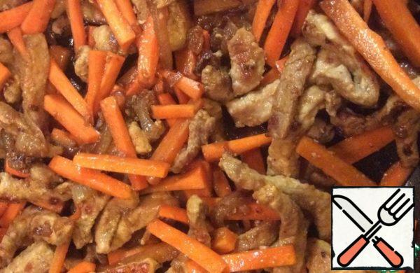 Put carrots to the meat and fry for 3 minutes.