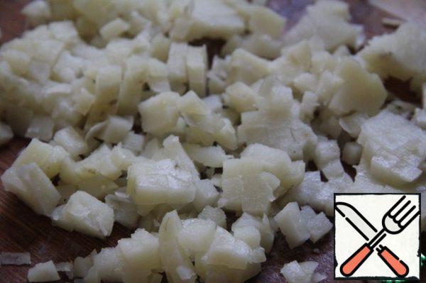 Boil potatoes, cool down, fill with cold water and, having cleaned, cut into cubes.