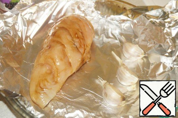 Put the fillets in a heat-resistant form, covered with foil. Next, lay out the garlic slices. Cover the chicken and garlic cloves with foil. Bake in a preheated 180 degree oven for about 20-25 minutes.
