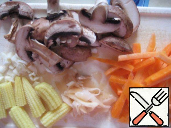 Soak the mushrooms;
cut vegetables: garlic, ginger - finely, carrots - large strips, mushrooms cut lengthwise into 4 parts, corn on the cob - into 3 parts.