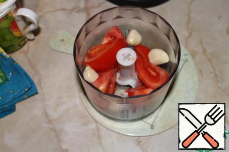 Take the tomato, cut in big slices and throw in a blender, then 4 cloves of garlic.