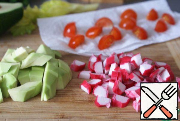 Cherry tomatoes can be used for the salad. Chop the cherry tomatoes and put them on a paper towel to drain a little water. Cut the avocado and crab sticks into cubes of approximately the same size.
