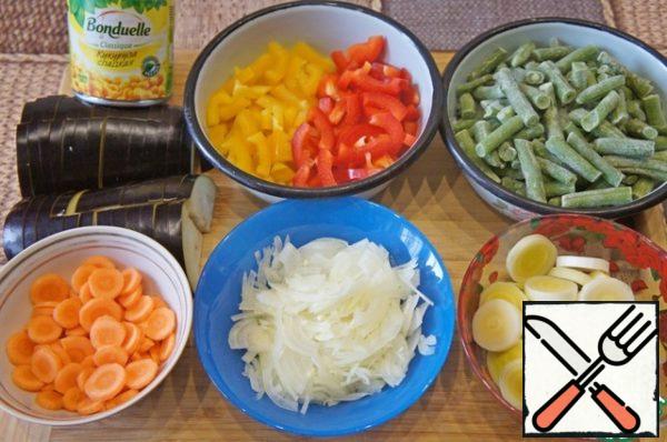 If the beans are fresh, they should be boiled, thrown into a colander, and then cut into pieces.
Finely chop the onion, cut the leek into slices. Bulgarian pepper (I had yellow and red in half) cut into strips, carrots - slices. Cut the eggplant lengthwise into 4 pieces, and then cut across into slices.
