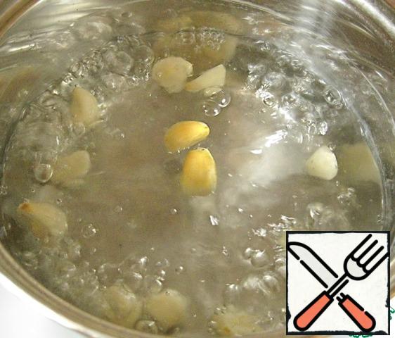 Peel the garlic and blanch for a minute in boiling salted water. With a slotted spoon to get the garlic out of the boiling water and drop a few minutes in cold water.