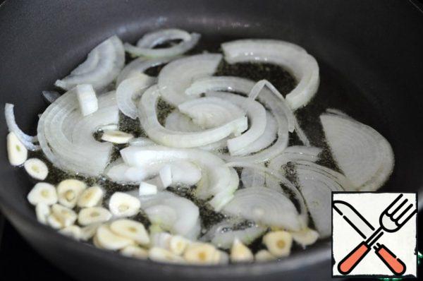 While the rice is cooking, prepare the dressing (for the soup). Cut onion into half rings, garlic into slices. It is ideal to cook this dish in a cauldron and on an open fire.
In the absence, take a saucepan with a thick bottom.
When the oil is hot, fry the onion and garlic.