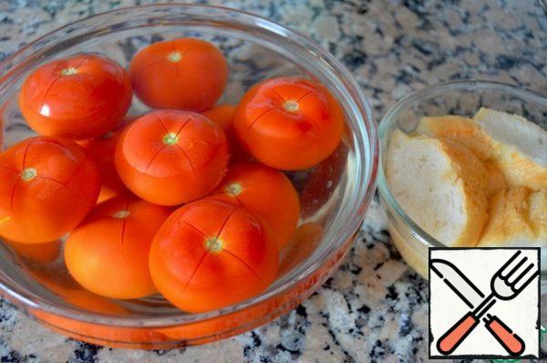 Put the tomatoes in a large bowl and pour boiling water over them. After 10 seconds, drain the water, and when the tomatoes cool down, remove the skin from them.
Put the bread in a bowl and pour water at room temperature.