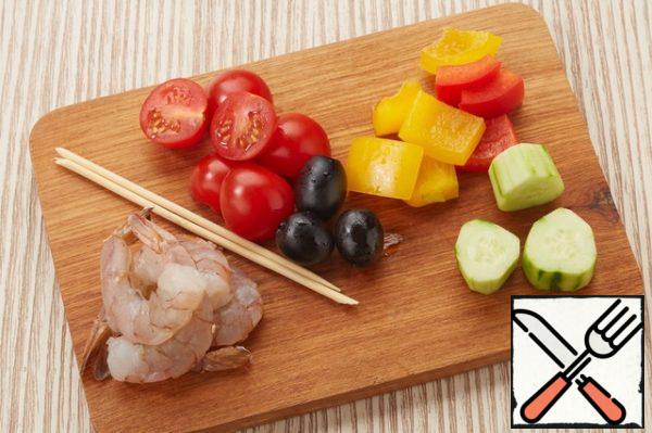 Soak the skewers in cold water for 10-15 minutes.
Peel the shrimp.
Cut the bell pepper into large pieces.
On one skewer, string two shrimp in combination with pepper. The other is cucumber, cherry tomatoes, pepper.
Put the shrimp on a skewer, season with salt, pepper and fry in a frying pan. Pour gazpacho into a martini glass, put skewers on top, insert straws and garnish with a basil leaf.