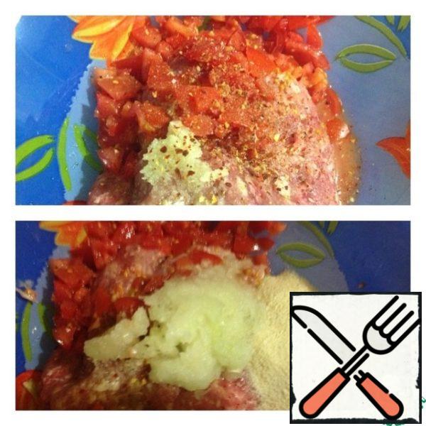 Put the noodles to cook.
Squeeze garlic into the minced meat, add spices, salt and pepper. Pour boiling water over one tomato and remove the skin. Cut into small cubes and add to the minced meat.
Grate the onion on a coarse grater, add semolina, chop parsley. Add 100-150 ml of water and knead the minced meat.