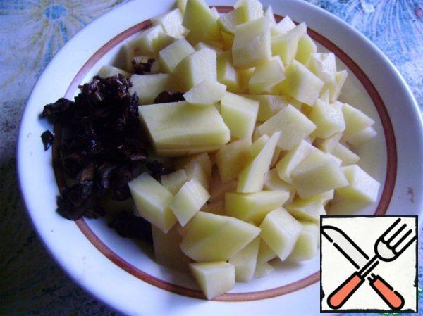 While stewed vegetables, potatoes cut into cubes. Squeeze the mushrooms and chop finely. Water in which soaked mushrooms add to the broth. There throw potatoes and mushrooms.