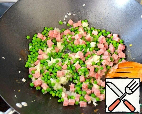 In a frying pan (wok) pour the remaining oil and add in order first ham and then peas. Next, put the remaining onions and stirring, fry all lightly in a pan. Make sure nothing gets burned!