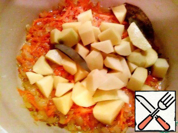 When the onions and carrots are soft, add the chopped potatoes, pepper and bay leaf. Pour water.
