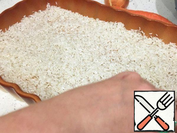 Form grease with sunflower oil and spread a uniform layer of well-washed rice.