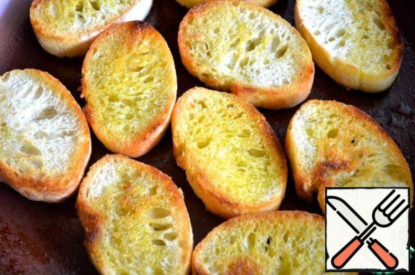 Cut the baguette into medium-thick slices and fry them in olive oil.
