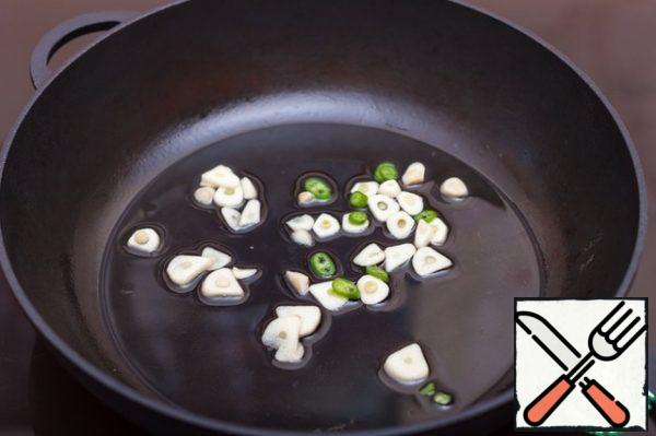 Preparing the sauce. Garlic cut into plates, fry with rings of hot pepper in olive oil until a bright aroma appears.
