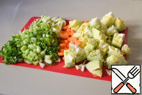 First, prepare the vegetables, to wash and peel.
Cut cabbage in half, cut out the stalk and cut into large pieces.
Carrots and leeks cut into circles.
Celery-pieces. The greens also cut.