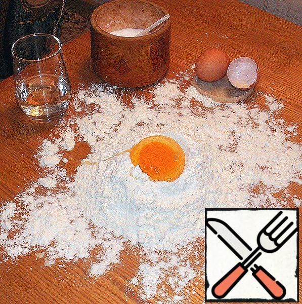 Sift flour, pour a slide on the Board, make a deepening in the flour, hammer egg, salt and gradually pouring water, knead the dough.