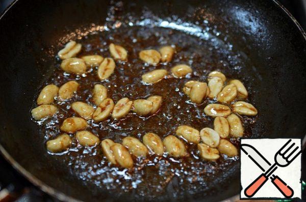 Then fry some peanuts in a pan. Add chicken broth or boiling water (100-140 g) and sesame oil. Let the sauce boil a little.