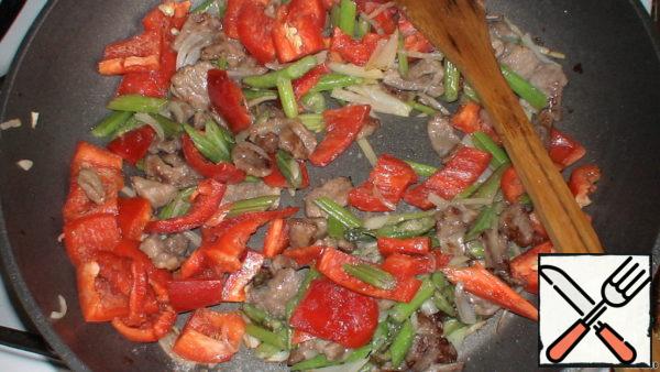 Then the bell pepper, fry for another 1 minute, sprinkle with salt, then add the tomato. Cut (not finely) 1 clove of garlic, add to the pan, stir and immediately turn off.