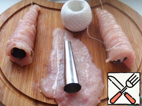 Wipe chicken fillet with olive oil and salt (1/2 tsp). Next, using cups with straws and confectionery yarn, roll chicken in the tube.