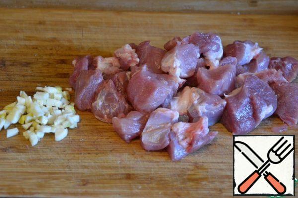 Cut the meat into pieces and chop the garlic.