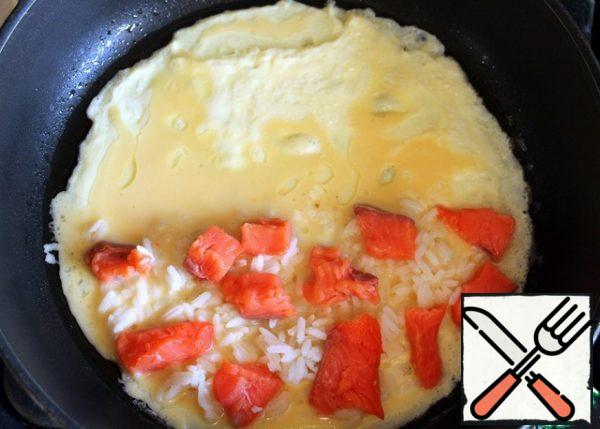 Pour 2/3 of the omelet mixture on a greased pan, put 1/3 of the finished rice bag  and pieces of salted salmon on one half omelet. Fry for about 1 minute.