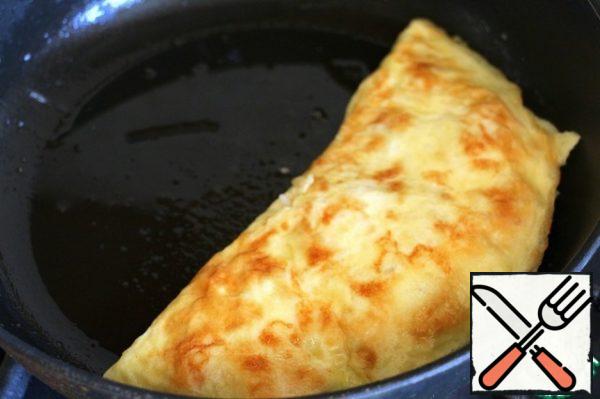 Carefully cover the filling with a spatula with the second half of the omelet.