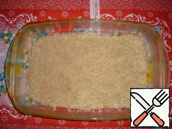 Rinse 2 cups of rice, put on a baking tray greased with sunflower oil.