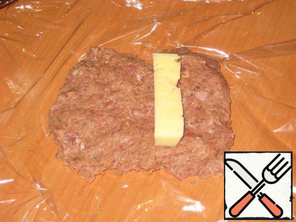Put the minced meat tortilla on the food film, smooth it out, put it out of the cheese and wrap the cheese in the filling, close the edges so that the cheese does not leak out.
