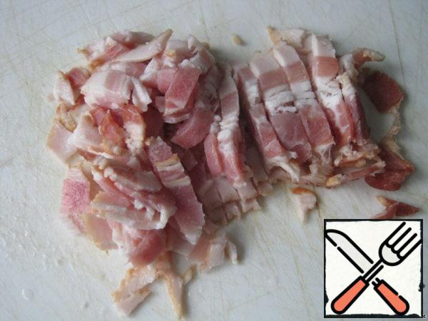 While preparing porridge, cut raw smoked bacon.