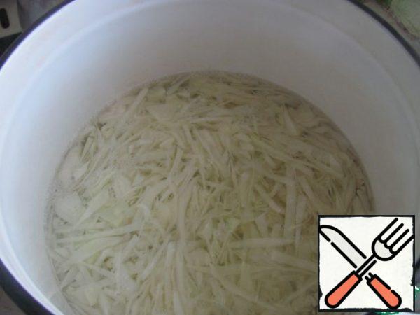 Finely chop the cabbage and pour salted boiled water for 5 minutes (if the cabbage is hard, then leave it longer). Flip into a colander, lightly apply with a spoon to remove excess water.
