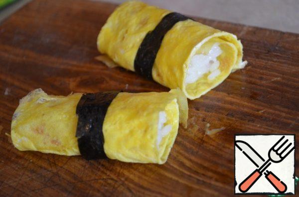 Wrap the rice in an omelet pancake, tie with a stripe of nori.