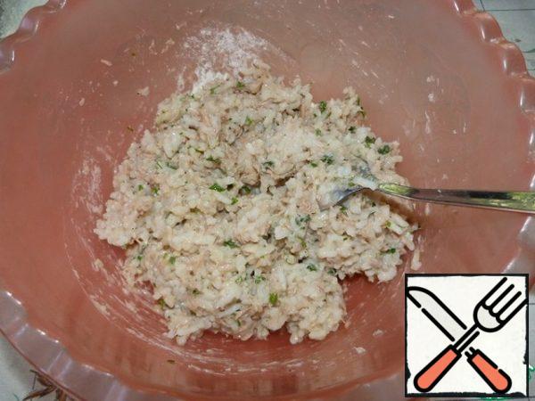Add 2 cups of cooled rice to tuna, drive in the egg, squeeze out garlic (if desired), cut greens, salt and pepper to taste, add flour (about 2 tablespoons). Mix everything well.