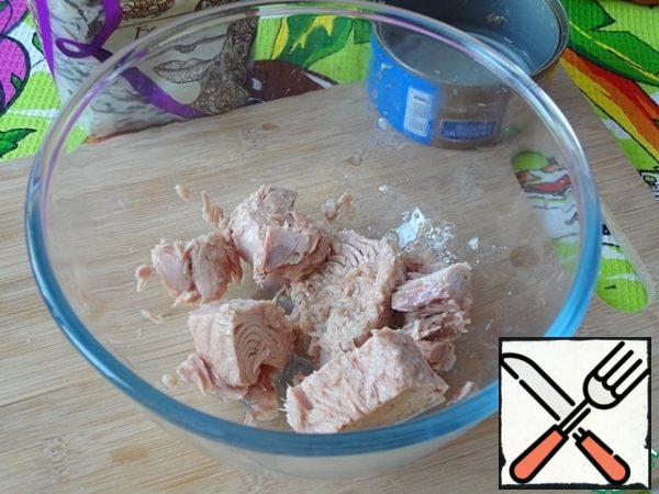 Drain the liquid from the tuna can and transfer the fish to a bowl.
