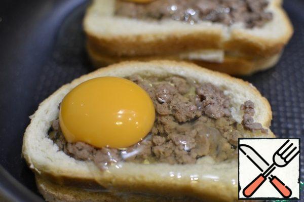 Spread the stuffing inside the sandwich. You need to spread so that there is as little space between the bread and the "frame" that would then the egg does not flow much. Divide on top of the egg, trying to keep the whole yolk, slightly potseluem Even if a little protein will leak, nothing to worry about. Send in a preheated 180 deg oven for 10 minutes, then sprinkle with crumbled cheese or grated cheese and send in the oven for 5 minutes. Be guided by your oven.