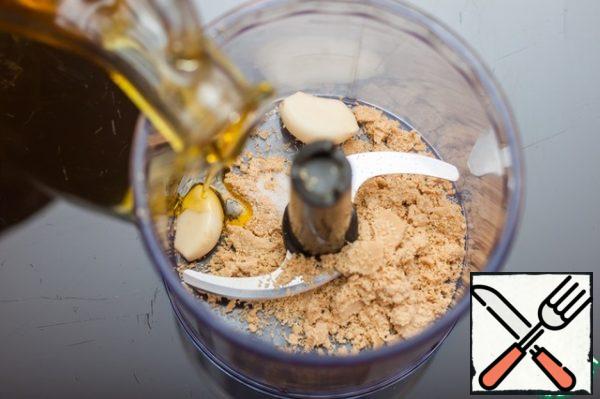 Transfer the sesame seeds to a blender, add garlic cloves, a little olive oil, salt and grind into a homogeneous paste.

