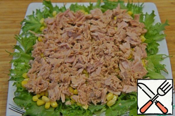 Tuna meat remove from the jar and crush slightly with a fork. Put on corn.