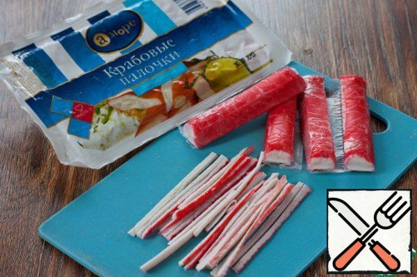 Defrost the crab sticks and cut into thin strips.
