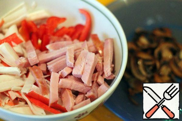 Mushrooms cut into plates and fry until Golden brown. Remove from the pan and cool. Crab sticks, ham and pepper should be cut into strips.