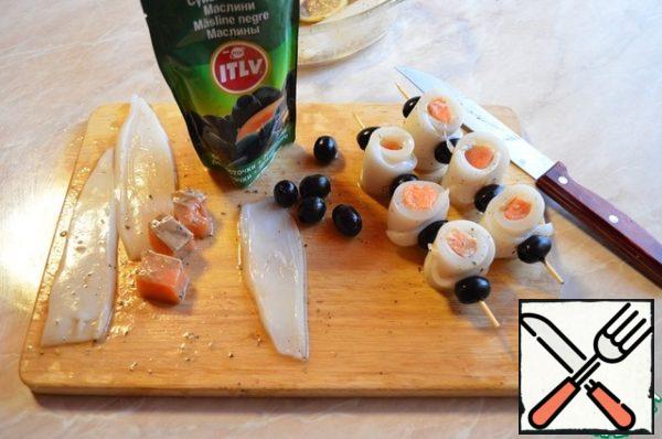Squid cut into 4 parts (to get from each squid 4 long strips). Cut the salmon into small cubes. Roll the squid with salmon into a roll, string on a skewer, alternating olives with a roll.