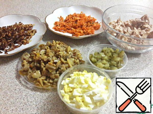Boil the thigh, cool it, cut into small pieces.
Boil the eggs, cool, chop finely.
Mushrooms cut into small pieces, fry, pepper.
Finely chop the cucumber.
Fry the onion and carrot separately.
Chop the garlic finely.