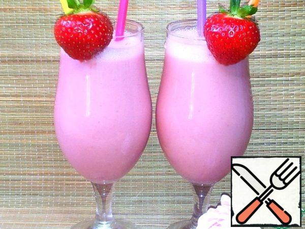 The glasses are decorated with strawberries and 2 straws are inserted.
