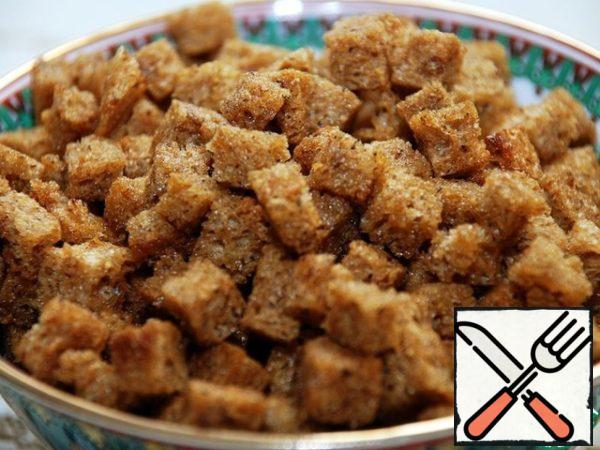 Cut the bread into slices, cut off the crust from them from all sides, cut into pieces like croutons. Fry in a frying pan with the addition of olive oil.
