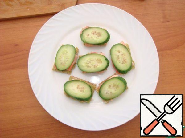 On fish put slice of cucumber. Cucumber-bread with avocado upside down. Decorate with dill sprigs and pomegranate seeds.